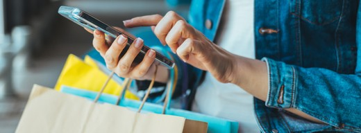 A woman holding shopping bags looking at her phone