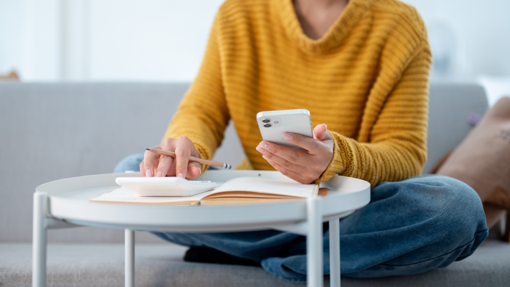 Close up of person using a phone and calculator