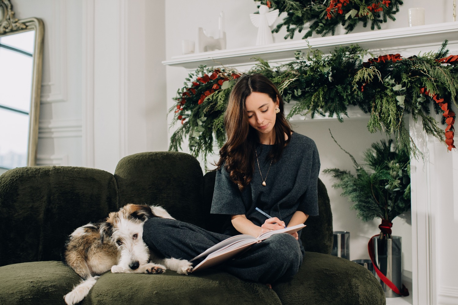 Woman sitting on sofa with dog while journaling